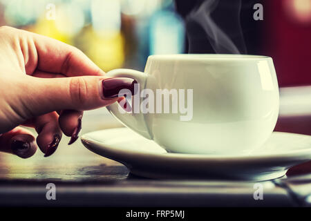 Donna con mano rosso chiodi curati tenendo una tazza di caffè. Foto Stock