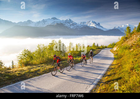 Quattro ciclisti su una tortuosa strada di montagna sul loro modo al serbatoio di Emosson lago delle Alpi sul confine della Francia e Svizzera. Foto Stock