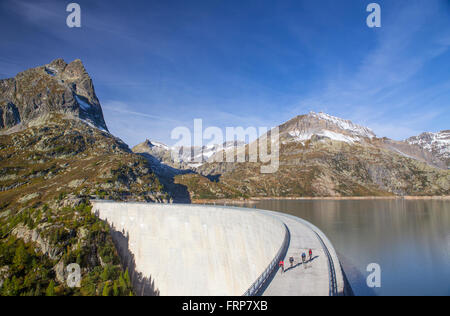 Quattro ciclisti sulla diga di Emosson serbatoio lago delle Alpi sul confine della Francia e Svizzera. Foto Stock