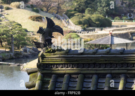 Shachihoko dettaglio del tetto sulla parte superiore di Jigen-do Santuario con Sawa-no-ike stagno nel retro, il Giardino Korakuen, Okayama, Giappone Foto Stock