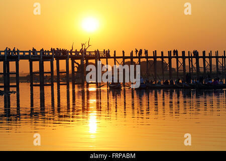 Le persone che attraversano la U Bein ponte che attraversa il lago Taungthaman al tramonto in Amarapura, Mandalay Myanmar (Birmania) Foto Stock