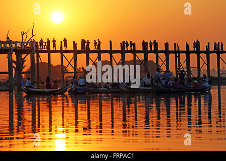 Le persone che attraversano la U Bein ponte che attraversa il lago Taungthaman al tramonto in Amarapura, Mandalay Myanmar (Birmania) Foto Stock