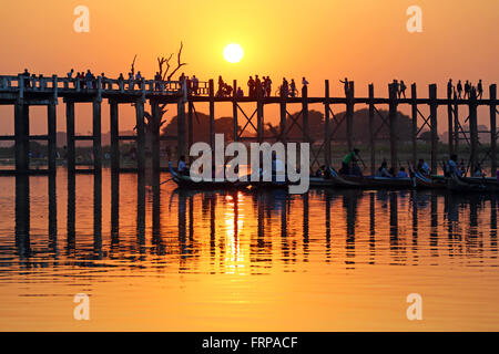 Le persone che attraversano la U Bein ponte che attraversa il lago Taungthaman al tramonto in Amarapura, Mandalay Myanmar (Birmania) Foto Stock