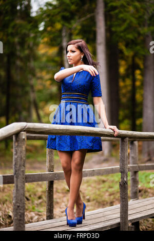 Bruna ragazza in vestito blu passeggiate al parco. Foto Stock