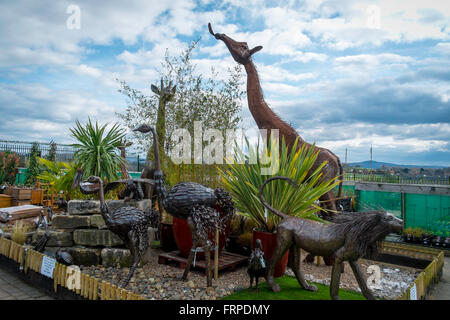 Una collezione di ornamenti da giardino in acciaio di grandi dimensioni le giraffe leoni e struzzi statue in un giardino suburbano center Foto Stock