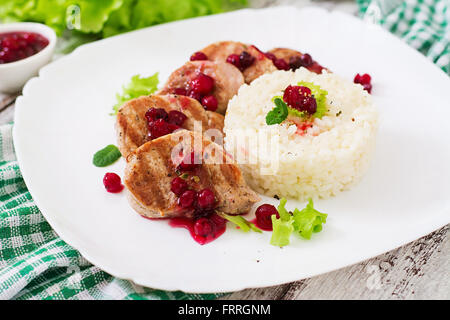 Medaglioni di maiale bistecca con salsa di mirtilli e un lato piatto di riso Foto Stock