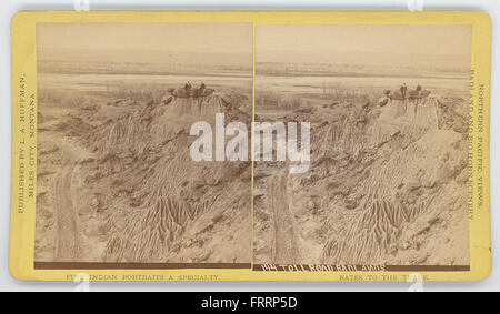 Una vista di una strada a pedaggio che passa attraverso le Badlands, mostrando il paesaggio rurale e il terreno accidentato. L'immagine cattura la strada che si snoda attraverso il suggestivo paesaggio, con la geologia unica delle Badlands visibile in lontananza. Foto Stock