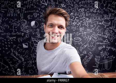 Hipster studente facendo prendendo selfie contro una grande lavagna Foto Stock