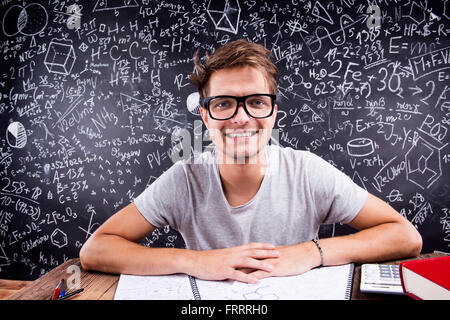 Hipster studente facendo il suo dovere nei confronti di una grande lavagna Foto Stock