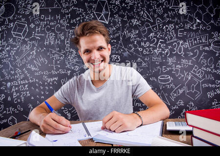 Hipster studente facendo il suo dovere nei confronti di una grande lavagna Foto Stock