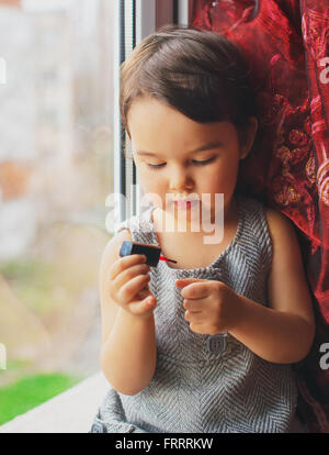 Piccolo bambino, carina ragazza toddler divertirsi giocando a casa con colorati per unghie facendo manicure Foto Stock