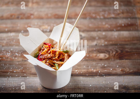 Tagliatelle con carne di maiale e le verdure in take-out box sul tavolo di legno Foto Stock