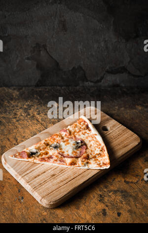 Un trancio di pizza sulla tavola di legno verticale Foto Stock