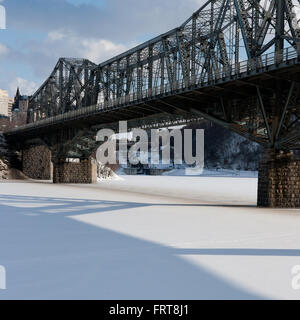 Le chiuse del canale Rideau sono incorniciate dal ponte Alexandra e da un fiume ghiacciato Ottawa. Foto Stock