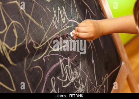 Bambino disegno a mano con un gessetto sulla lavagna Foto Stock