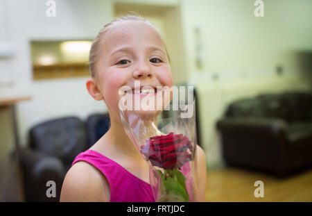 Una giovane ragazza pone con una rosa rossa a seguito del suo grado 1 esame di balletto presso la Reale Accademia di danza a Londra Foto Stock