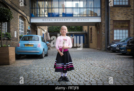 Una giovane ragazza pone con una rosa rossa a seguito del suo grado 1 esame di balletto al di fuori della Royal Academy of Dance di Londra Foto Stock