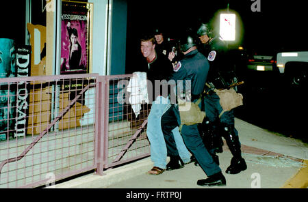 College Park, Maryland, USA, 1 Aprile, 2002 membri del Prince Georges County dipartimento di polizia nel tumulto di arresto marcia uno di circa 17 studenti dell'Università del Maryland durante una sommossa scoppiata dopo l'Università del Maryland sconfitto Indiana la rivendicazione del titolo alla NCAA di pallacanestro degli uomini di campionato. È stato Maryland il primo college basketball titolo e la vittoria di ventole inviato in una frenesia. Una stima di 5.000 ha colpito le strade nella celebrazione. Alimentato da un consumo eccessivo di alcol, il mob accesa nei bidoni della spazzatura e divani sul fuoco per le strade. Credito: Mark Reinstein Foto Stock