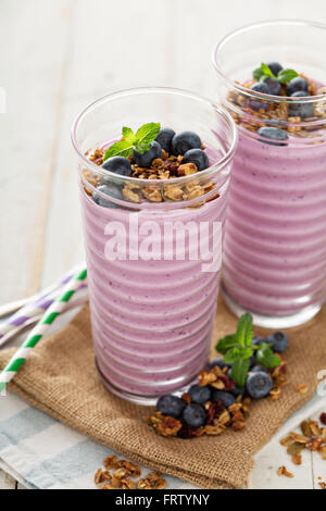 Frullato di mirtilli con granola in bicchieri alti Foto Stock