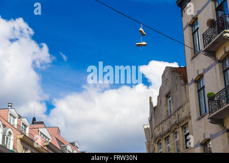 Sneakers pendente dal filo elettrico contro il cielo blu e chiaro a Bruxelles, in Belgio Foto Stock