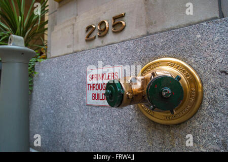 Golden idrante antincendio degli sprinkler in collegamento una parete in New York City. Foto Stock