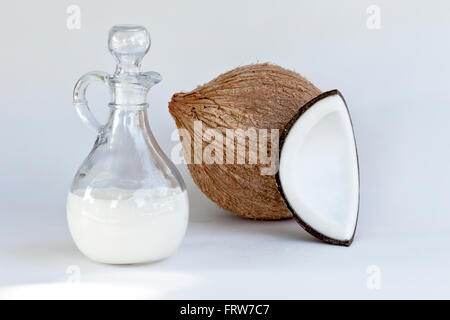 Semi solido olio di noce di cocco nella caraffa di vetro, interi & quartered dado. Foto Stock