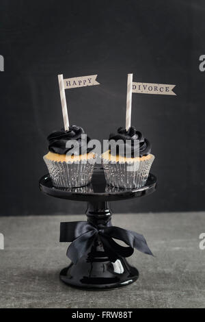 Due tortine con colore nero topping crema di burro e pennons su una torta di stand Foto Stock