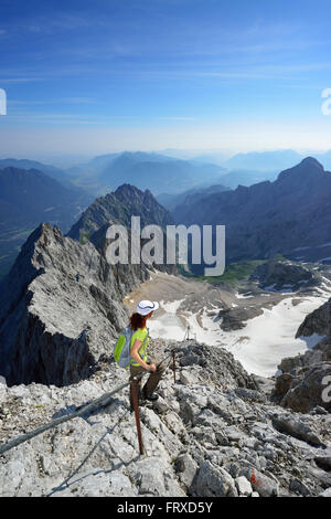 Donna ascendente sulla via ferrata di Zugspitze, ghiacciaio Hoellentalferner in background, Wetterstein mountain range, Alta Baviera, Baviera, Germania Foto Stock