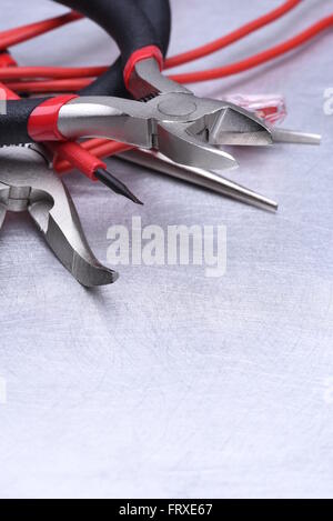 Strumenti per elettricista e i cavi grigio sulla superficie metallica Foto Stock