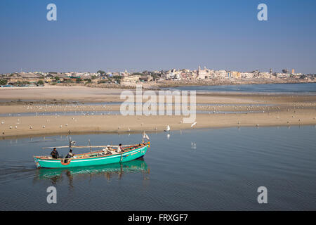 Barca da pesca e uccelli di mare sulla spiaggia vicino al porto ingresso, Porbandar, Gujarat, India Foto Stock