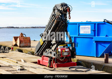 Torhamn, Svezia - 18 Marzo 2016: una gru da cantiere è montato un galleggiante per utilizzare il sollevamento in acqua di mare. Pier con contenitore Foto Stock