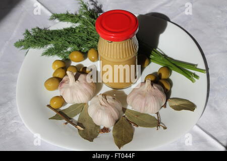 Scatola con mostarda, il ciuffo di fresco giardino del trapano, olive, tre teste di rosa piccante aglio Aroma, foglie di alloro ingredienti Foto Stock