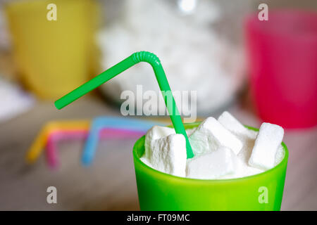 Primo piano della verde vetro plastica con paglia pieno di zucchero e cubetti di zucchero. Concetto di immagine per troppo zucchero in acque gassate Foto Stock