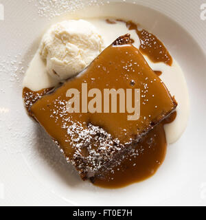 Sticky toffee pudding servito con gelato alla vaniglia a Londra, Inghilterra. Foto Stock