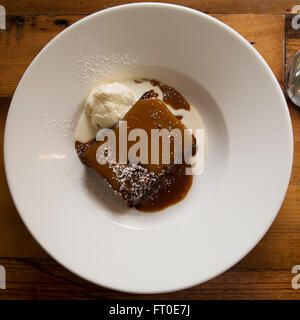 Sticky toffee pudding servito con gelato alla vaniglia a Londra, Inghilterra. Foto Stock