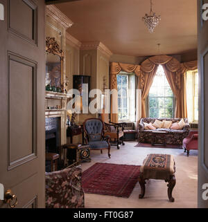 Porte aperte di stile Georgiano drawing room con swagged e tailed tende su una finestra di baia Foto Stock