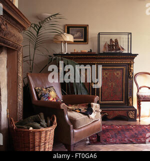 Brown sedia in pelle ed ornato antica credenza nel vecchio salotto Foto Stock