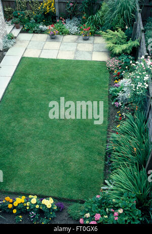 Gli uccelli vista di un neo turfed prato con bordi di piante annue colorati in un recente fatto giardino suburbano Foto Stock