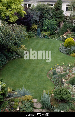 Gli uccelli vista di una nuova curva falciata prato in giardino suburbano con frontiere rockery Foto Stock