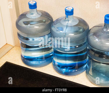 Tre 5 gallone di bottiglie di acqua sul pavimento di una zona di stoccaggio in un ufficio. Stati Uniti d'America. Foto Stock