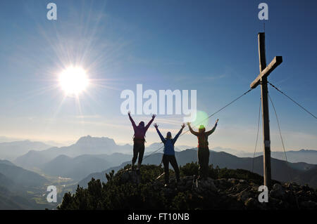Gli escursionisti femmina tifo accanto al vertice di croce sul monte Steinplatte, Waidring, Tirolo, Austria Foto Stock