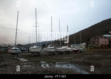 Yacht ormeggiati fino a Porlock Weir in attesa che la marea di venire in e impostare contro un profondo meditabondo molla sky, minacciando le tempeste. Foto Stock