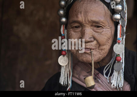 Akha vecchia donna in abiti tradizionali di fumare un tubo vicino a Kyaing Tong, Kentung, Stato Shan, MYANMAR Birmania Foto Stock