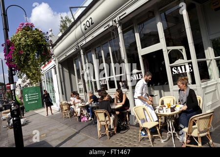 Donna gustando la prima colazione sulla Westbourne Grove, Notting Hill, London, England, Regno Unito Foto Stock