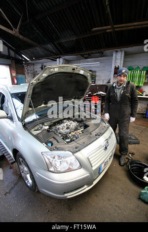 Meccanico nel garage in auto con il cofano aperto Foto Stock