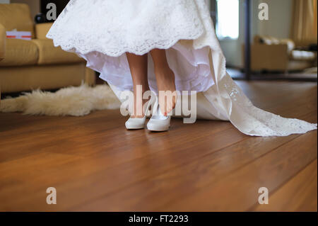 Sposa mette sulle scarpe in camera Foto Stock