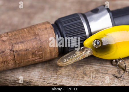 Primo piano Il sughero impugnatura della canna da pesca con esca sulla tavola di legno dello sfondo. Concept design per acqua dolce all'aperto business attivo c Foto Stock