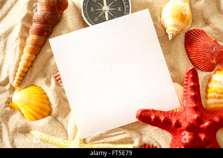 Conchiglie, bussola e carta bianca sulla sabbia Foto Stock