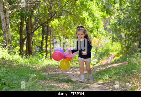 Bambina giocando in autunno park con palloncini Foto Stock