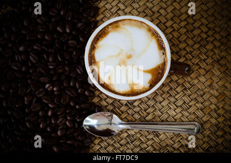 Caffè torrefatto in grani e caffè caldo su sfondo di bambù Foto Stock